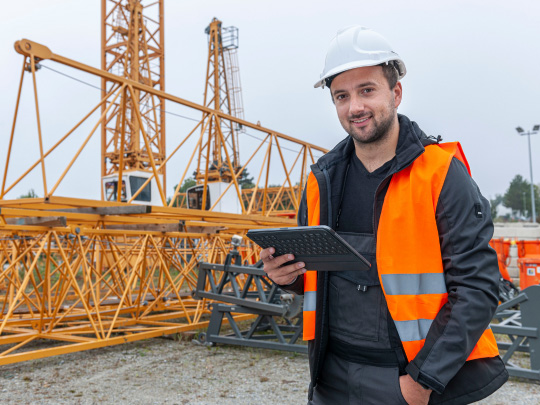Mitarbeiter mit Tablet vor Baukran
