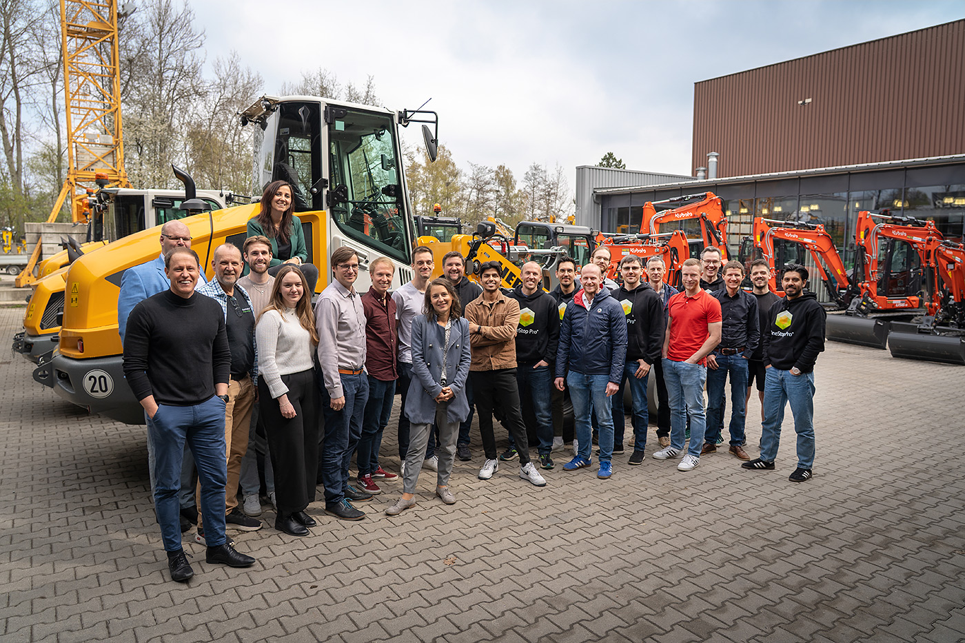 Gruppenfoto OneStop Pro Team vor Baumaschinen